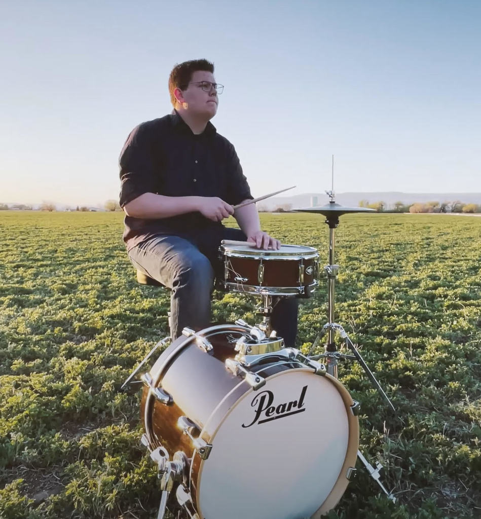 Aaron Tuchardt playing drums in a field