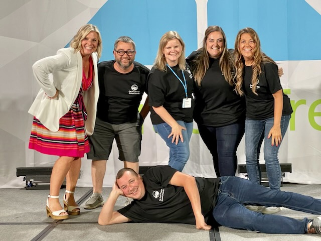 5 elementary staff members on stage posing for a picture. 